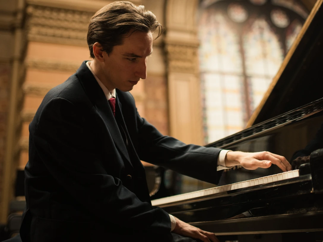 Weltklassik: Serafym Ivanov Pianist in elegantem Anzug spielt konzentriert am Flügel in einem historischen Saal.