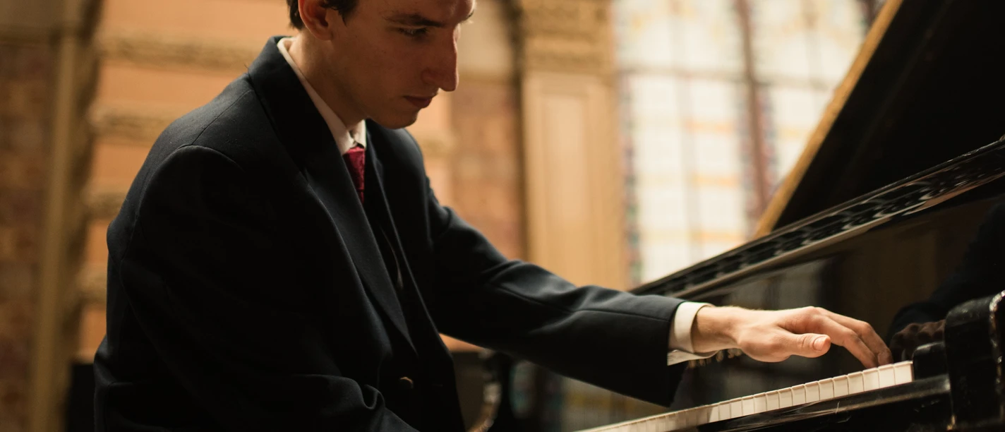 Weltklassik: Serafym Ivanov Pianist in elegantem Anzug spielt konzentriert am Flügel in einem historischen Saal.