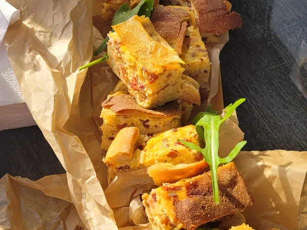 Kulinarische Stadtführung Verschiedene, frisch gebackene Brotscheiben auf braunem Papier, mit Rucola-Blättern garniert.