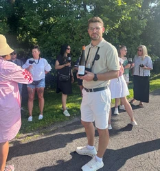 Weinwandern Timo Strauss mit einer Weinflasche in der Hand steht vor einer Gruppe Menschen mit Weingläsern in der Hand