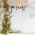 In einem Raum mit weißen Wänden, an denen eine Uhr hängt, ist eine große Blumenranke installiert.