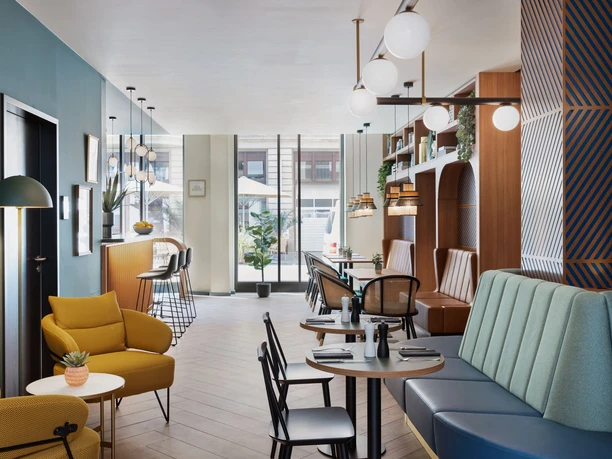 Seating area with colorful and cozy benches and armchairs in the Koko Café & Bar at the Stay Kooook Hotel Leipzig in Gottschedstraße