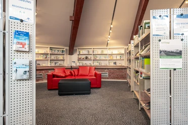 In der Bücherei Seevetal Eine einladende Leseecke mit roten Sofas umrahmt von Bücherregalen in behaglicher Bücherei-Atmosphäre.
