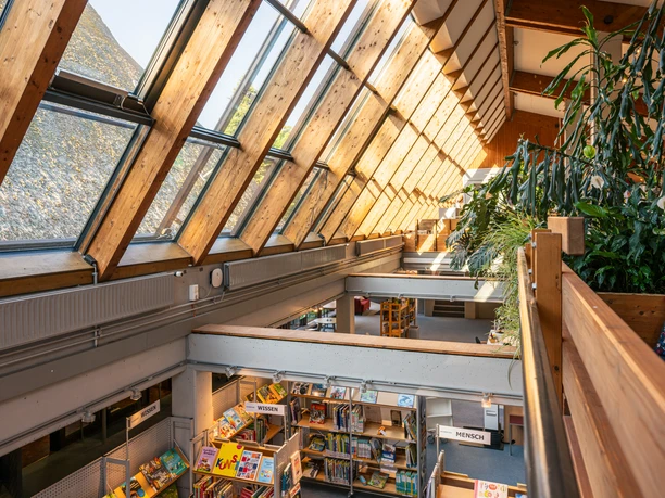 In der Bücherei Seevetal Das Bild zeigt das helle Innere der Bücherei Seevetal, das durch schräg einfallendes Sonnenlicht beleuchtet wird. Fensterfronten und Holzträger prägen die offene Architektur.