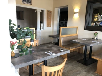 Einladender Restaurant-Innenbereich mit Holzmöbeln, grünen Pflanzen und sanfter Wandbeleuchtung.Inviting restaurant interior with wooden furniture, green plants and soft wall lighting.Indbydende restaurantinteriør med træmøbler, grønne planter og blød vægbelysning.Uitnodigend restaurantinterieur met houten meubels, groene planten en zachte muurverlichting.