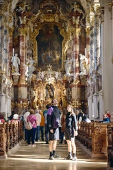 Radpilgern - Wieskirche Innenansicht einer barocken Kirche mit kunstvoll verzierten Wänden und Besuchern.
