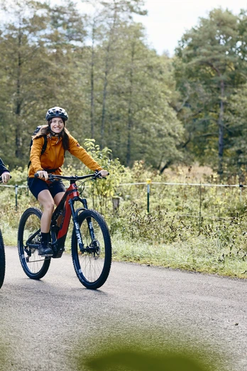 Radpilgern-Kraftquelle Zwei Menschen fahren mit Mountainbikes auf einem Weg, umgeben von Bäumen.