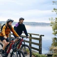 Radpilgern - Kloster Bernried Zwei Radfahrer auf einem Weg am See in herbstlicher Landschaft.