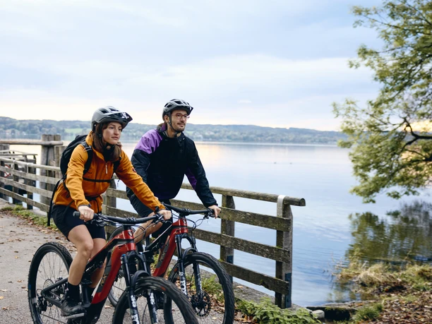 Radpilgern - Kloster Bernried Zwei Radfahrer auf einem Weg am See in herbstlicher Landschaft.