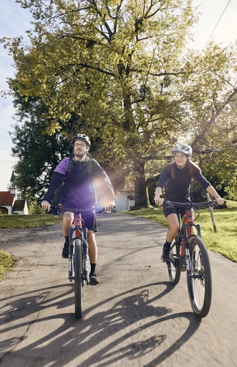 Radpilgern - Auerberg Bernbeuren Zwei Radfahrer auf einem Landweg bei sonnigem Wetter, umgeben von grüner Landschaft.