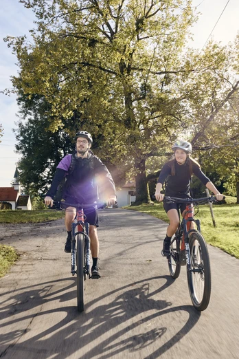 Radpilgern - Auerberg Bernbeuren Zwei Radfahrer auf einem Landweg bei sonnigem Wetter, umgeben von grüner Landschaft.