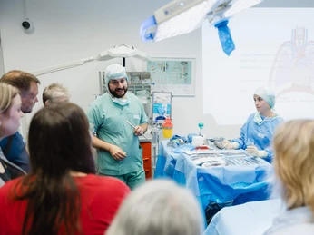 Night of Technology Cologne Eine Gruppe von Menschen lauscht einem Vortrag in einem Operationssaal, geleitet von medizinischem Personal.A group of people listen to a lecture in an operating theater, led by medical staff.