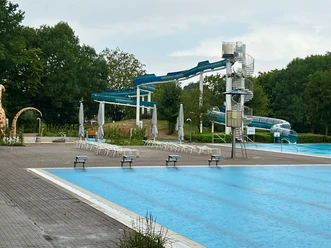 Freizeitbad Münchehagen Freizeitbad Münchehagen: Großer Außenbereich mit Wasserrutsche, umgeben von Bäumen und Liegestühlen.