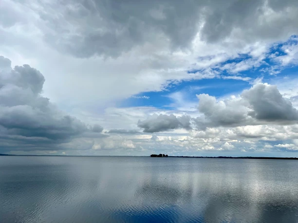Weite Wasserfläche des Steinhuder Meeres unter wechselhaftem Himmel mit dramatischen Wolkenformationen.