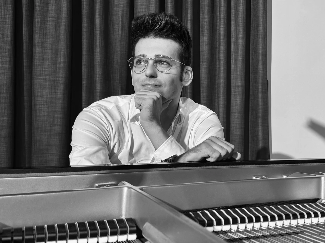 Jonas Becker.jpg Ein Mann sitzt nachdenklich am Klavier