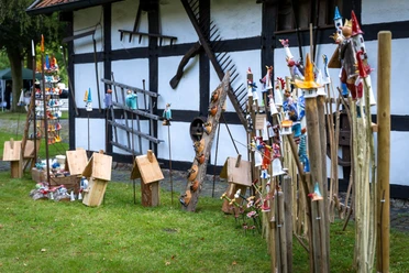 Kunst_Handwerkermarkt 2024.jpg Bunte Kunsthandwerke aus Holz und Keramik vor historischem Fachwerkhaus in Aschen
