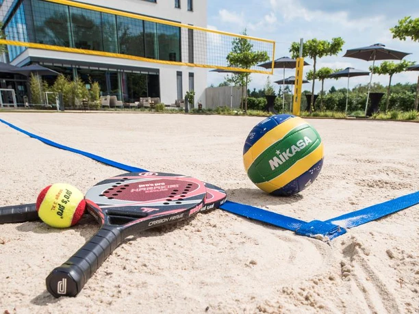 TeamOlympiade Sportartikel liegen auf einem Beach-Volleyball-Feld.