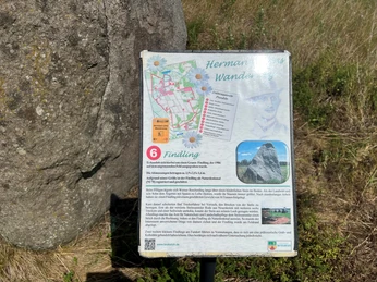 Findling Brokeloh Ein Findling im Gras mit einer informativen Tafel, die Details zur Geschichte und zur Lage bietet.