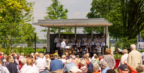 shanty-festival-kurpark-buehne Shanty Chor auf der Freilichtbühne am Zwischenahner Meer, im Vordergrund interessierte, ältere Zuhörer