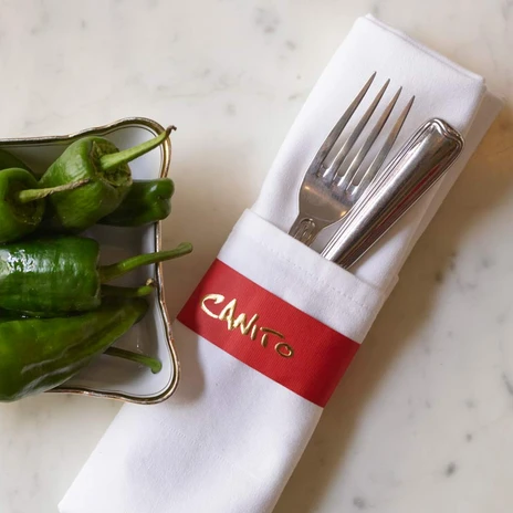 Canito l'acqua - Mediterrane Küche auf Leipzigs Kanälen Grüne Pepperoni in einer Tapas-Schale und ein in eine weiße Stoffserviertte gewickeltes Bestellset