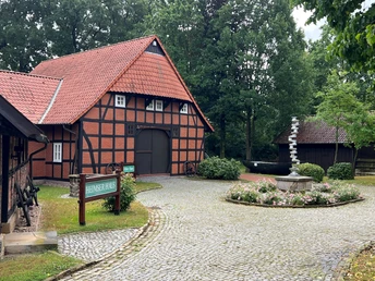 Heringsfängermuseum Heimsen Fachwerkgebäude mit rotem Satteldach und gepflegtem Vorplatz. Links ein Schild: "Heimser Haus".