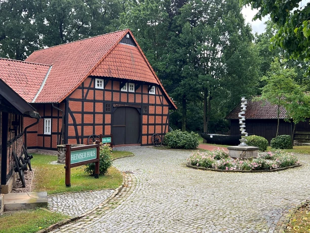 Heringsfängermuseum Heimsen Fachwerkgebäude mit rotem Satteldach und gepflegtem Vorplatz. Links ein Schild: "Heimser Haus".