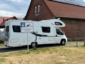Wohnmobilstellplatz neben einem historischen Backsteingebäude mit Solarpanelen und Poitou-Eselweide.