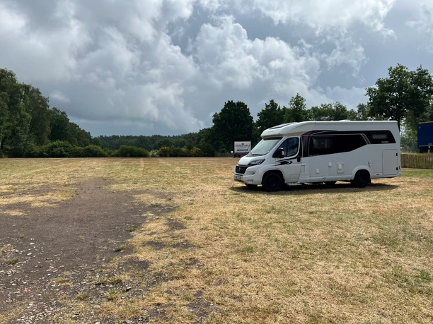 Wohnmobilstellplatz Bickbeernhof (2).jpg Ein Wohnmobil steht auf einem weitläufigen, grasbewachsenen Stellplatz unter einem bewölkten Himmel.