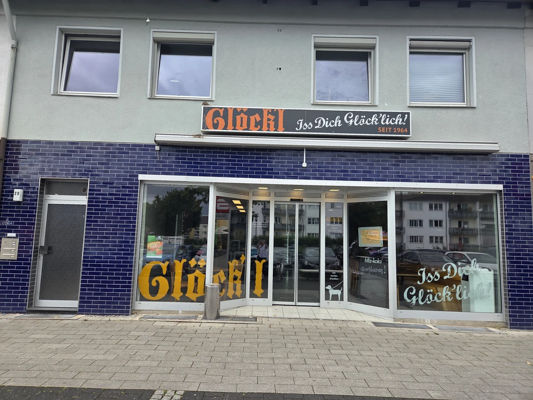 Glöck'l Eingang eines Geschäfts mit blauen Fliesen und großen Fenstern. Oben das Schild "Glöck'l".
