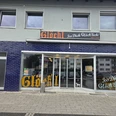 Glöck'l Eingang eines Geschäfts mit blauen Fliesen und großen Fenstern. Oben das Schild "Glöck'l".