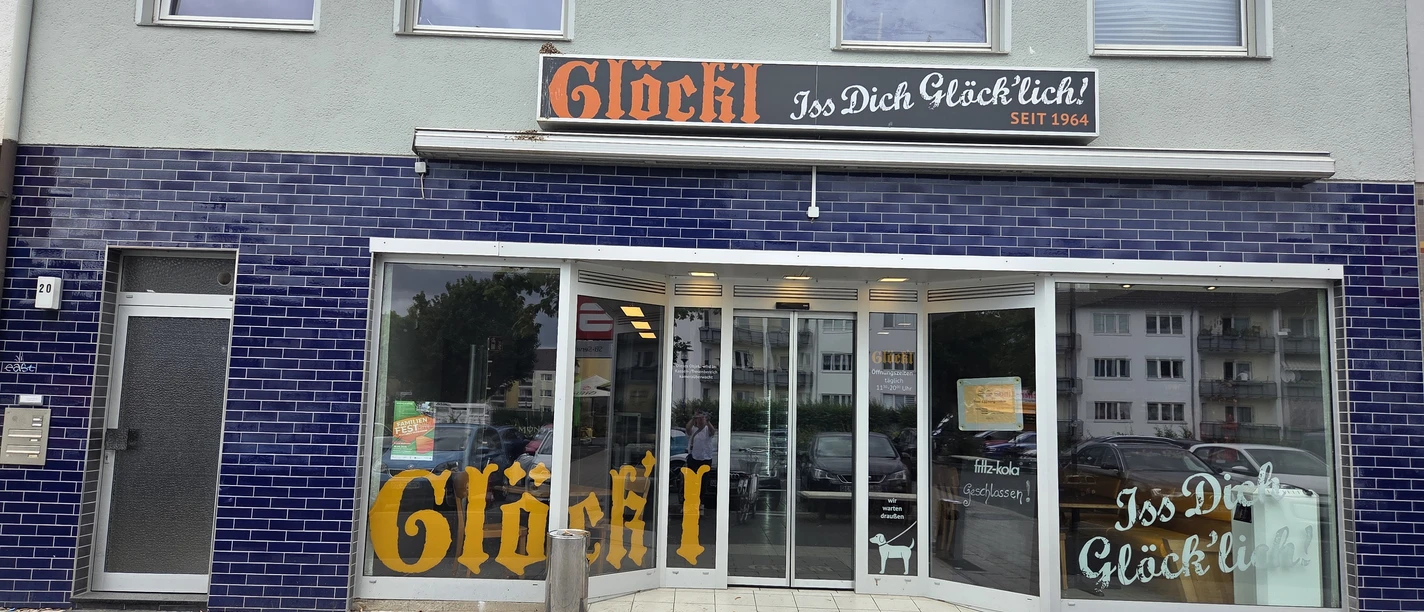 Glöck'l Eingang eines Geschäfts mit blauen Fliesen und großen Fenstern. Oben das Schild "Glöck'l".