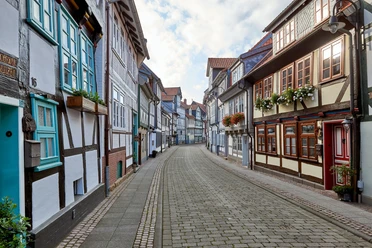 WF-Krumme-Strasse-Fachwerkgasse.jpg Schmale Straße mit alten Fachwerkhäusern und Blumen an Fenstern.