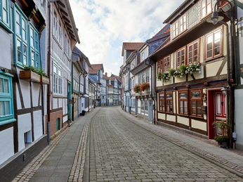 WF-Krumme-Strasse-Fachwerkgasse.jpg Schmale Straße mit alten Fachwerkhäusern und Blumen an Fenstern.