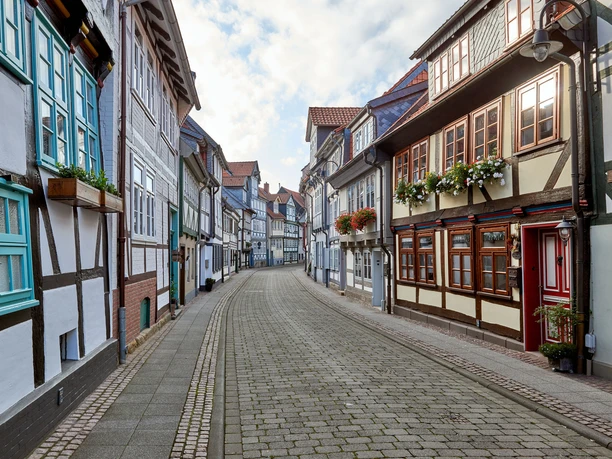 WF-Krumme-Strasse-Fachwerkgasse.jpg Schmale Straße mit alten Fachwerkhäusern und Blumen an Fenstern.