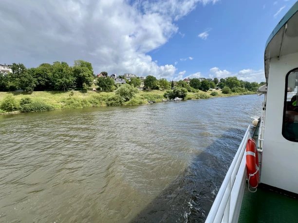 Badener Berge Flusslandschaft mit bewaldeten Hügeln im Hintergrund, teilweiser Blick von einem Schiff aus auf die Ufer.