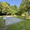Bouleanlage in Backemoor Freiluft-Boulefeld mit Sandfläche, umgeben von Bäumen und Rasen, bei sonnigem Himmel