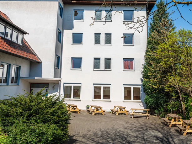Gästehaus in der Jugendherberge Velbert Jugendherberge Velbert: Vierstöckiges Gebäude mit weißer Fassade, rotes Dach, umgeben von Bäumen.
