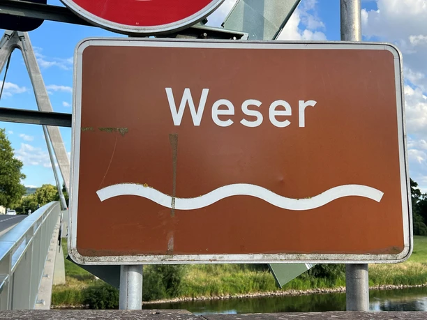 Brown sign with the white lettering "Weser" and a symbolic wavy line underneath.