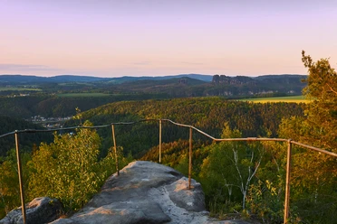 Uitkijkpunt Kohlbornstein met uitzicht op de markante Schrammsteine bij zonsondergang.