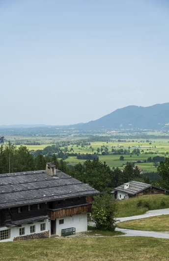 Himmlisch genießen - Glenleiten Altes Bauernhaus mit Schieferdach in grüner Landschaft und Blick auf Berge.