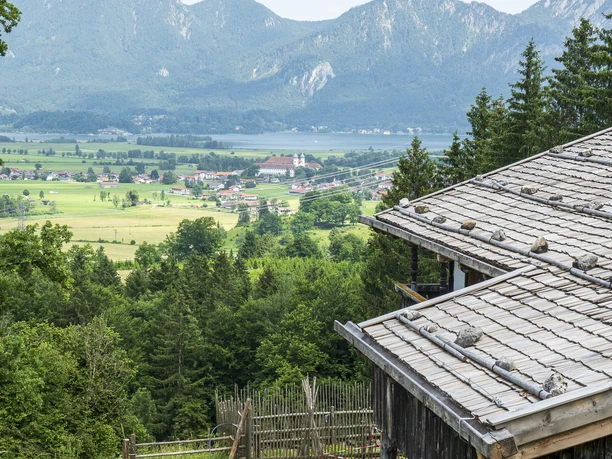 Freilichtmuseum Glentleiten Alte Holzhütte in einer grünen Landschaft mit Bergen im Hintergrund.