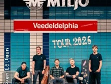 Fünf Bandmitglieder posieren lässig vor einer Wand mit dem Schriftzug "Miljö Veedeldelphia Tour 2026".