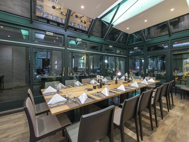 Wintergarten im Restaurant Blattwerk im Fletcher Hotel-Restaurant Waldhotel Nordrhein-Westfalen Restaurant Wintergarten mit elegant gedecktem Esstisch unter einem modernen Glasdach in Heiligenhaus.