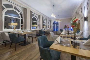 Gastraum im Restaurant Blattwerk im Fletcher Hotel-Restaurant Waldhotel Nordrhein-Westfalen Gastraum im Restaurant Blattwerk mit gedeckten Tischen, grün-blauen Stühlen und großen Fenstern.