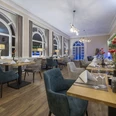 Gastraum im Restaurant Blattwerk im Fletcher Hotel-Restaurant Waldhotel Nordrhein-Westfalen Gastraum im Restaurant Blattwerk mit gedeckten Tischen, grün-blauen Stühlen und großen Fenstern.
