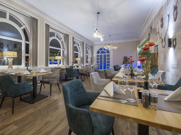 Gastraum im Restaurant Blattwerk im Fletcher Hotel-Restaurant Waldhotel Nordrhein-Westfalen Gastraum im Restaurant Blattwerk mit gedeckten Tischen, grün-blauen Stühlen und großen Fenstern.