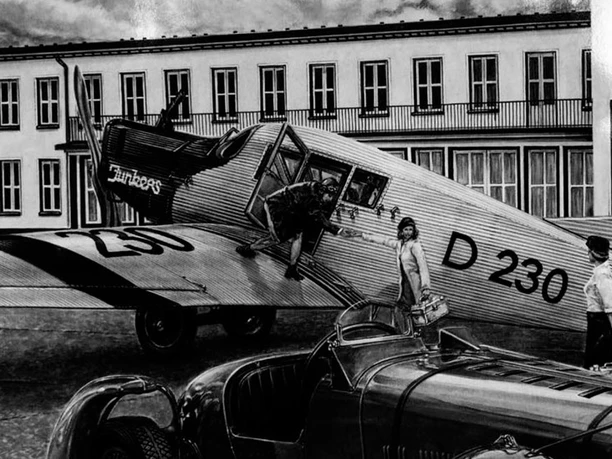 Historische Ansicht des Flughafens Butzweiler Hof Köln Ein historisches Flugzeug, eine Junkers Ju 52, steht vor einem alten Flughafengebäude.
