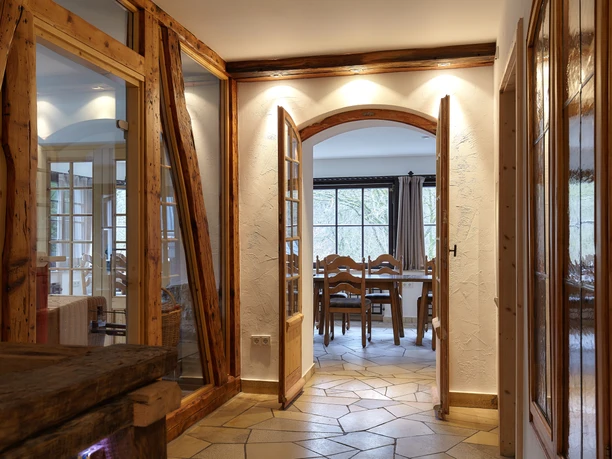 Aufenthaltsraum Ein einladender Flur mit Holzbalken führt zu einem hellen Speisezimmer mit rustikalen Holzmöbeln.