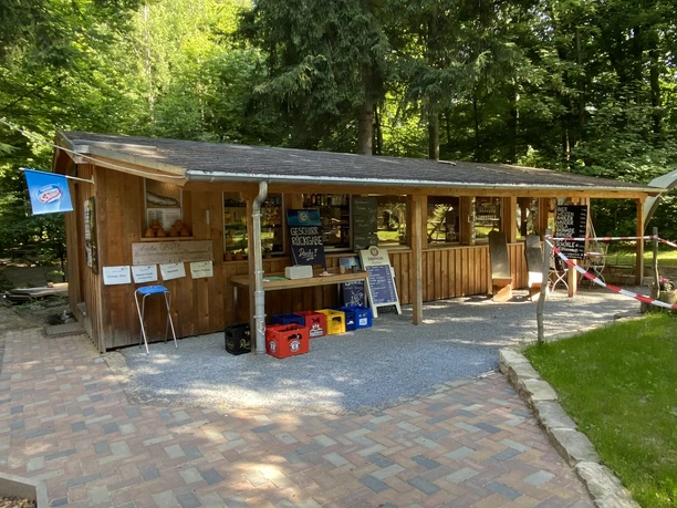 A rustic beer garden with a wooden hut in the forest, beer tables and benches invite you to linger.