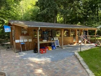 Bergwirtschaft Steinerner Tisch Biergarten Ein ländlicher Biergarten mit Holzhütte im Wald, Biertische und -bänke laden zum Verweilen ein.